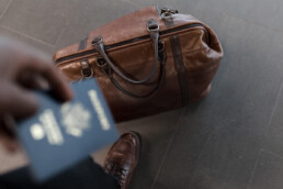 man holding passport by travel bag